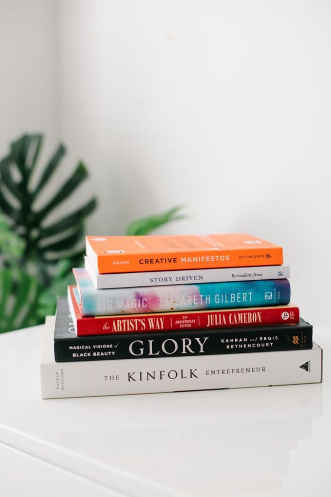 A neatly stacked pile of inspirational and creative books on a white surface.