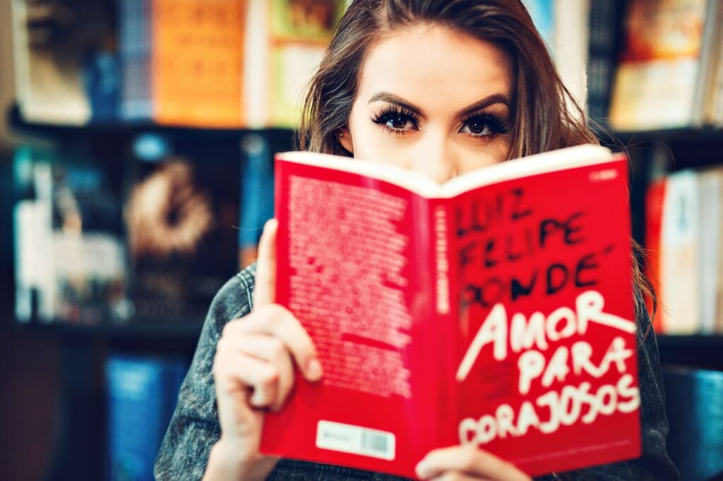 Portrait of a woman reading Amor Para Corajosos in a library.